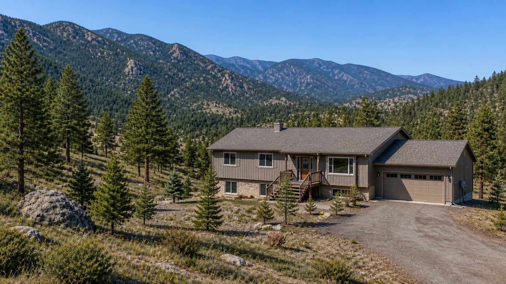A modest Evergreen-style raised-ranch home with a two-car garage on a maintained mountain lot beneath forested rocky ridges.