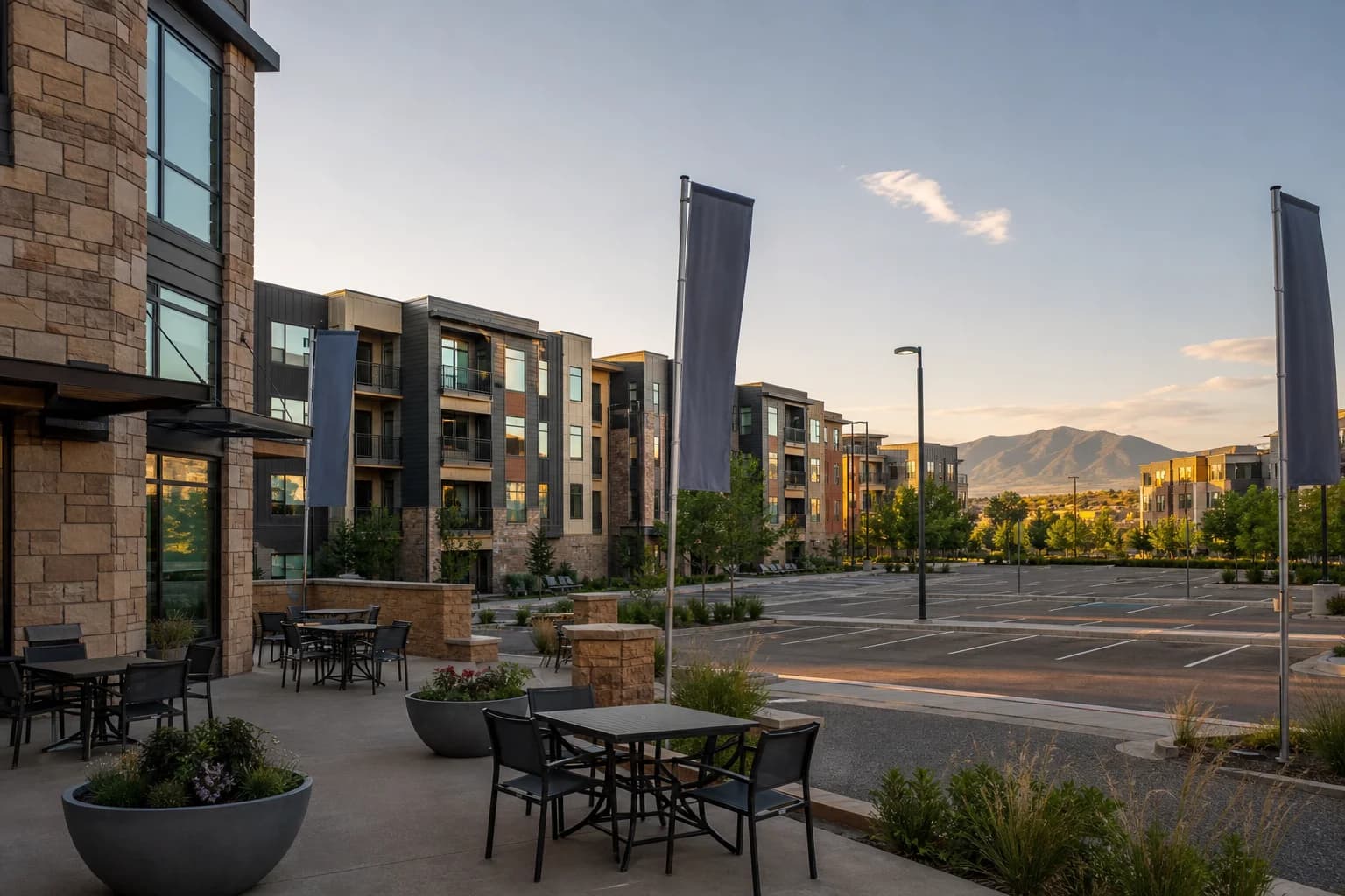 Quiet late-day view of a modern Denver-metro apartment complex courtyard and parking area, suggesting soft lease-up conditions rather than a permanent discount market.